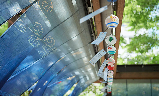 Fluttering wind chimes. A noren (curtain) with a nautical design is behind.